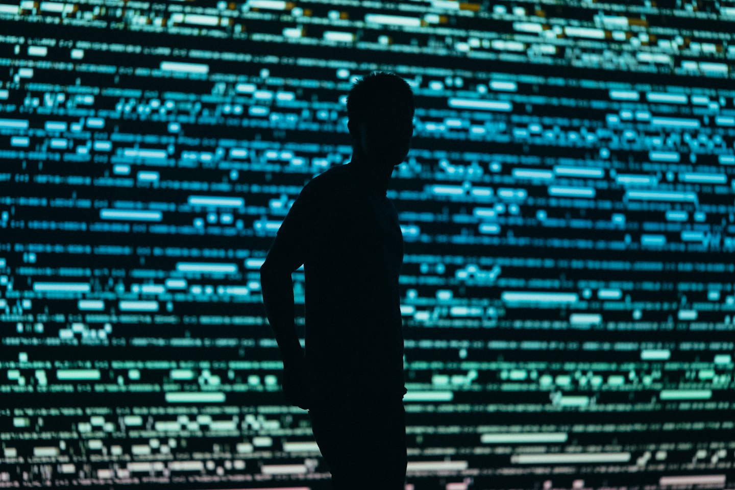 Person vor einem digitalen Bildschirm mit leuchtenden Daten im Silhouett.